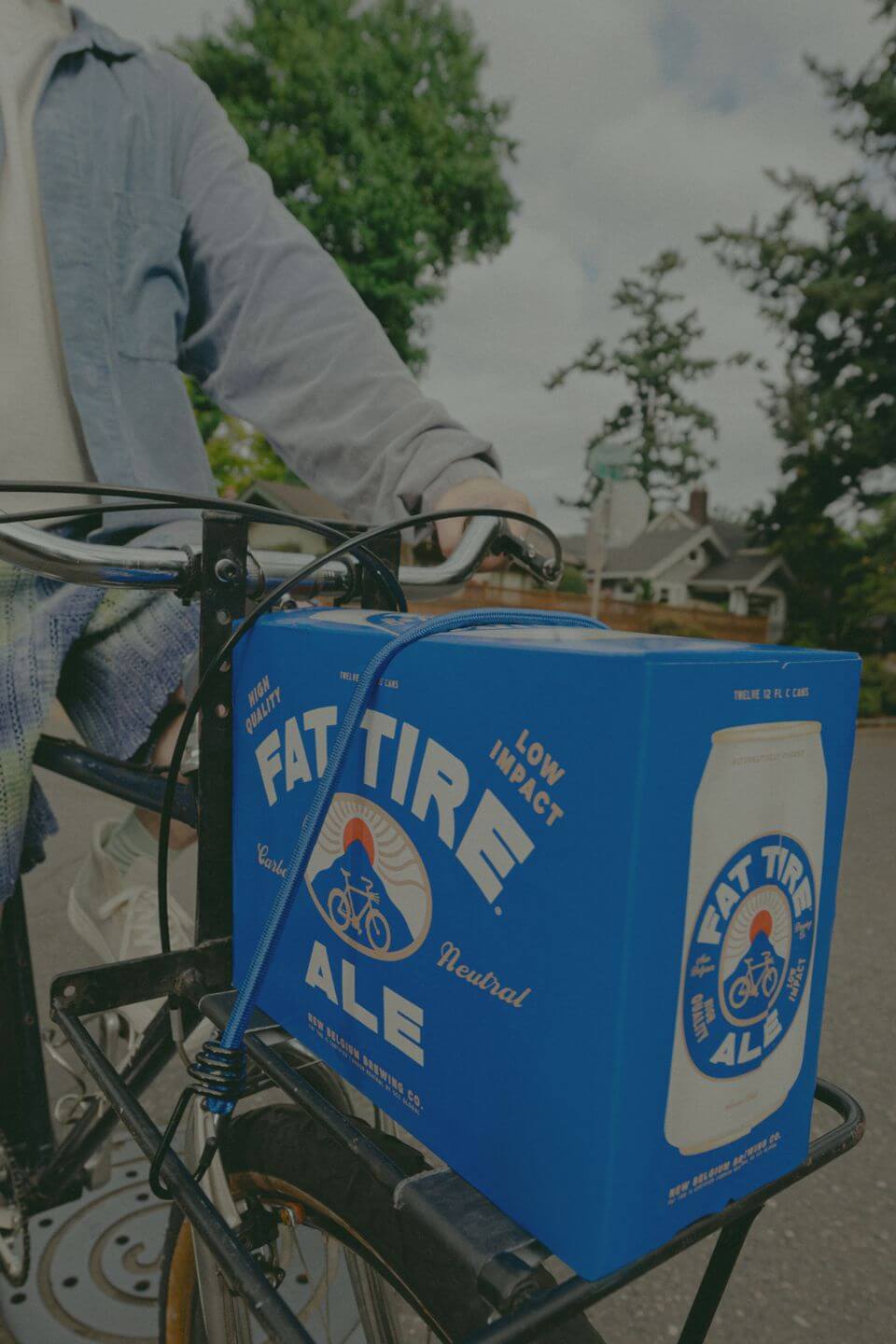 Man on bike with Fat Tire 12-pack strapped to the front. 